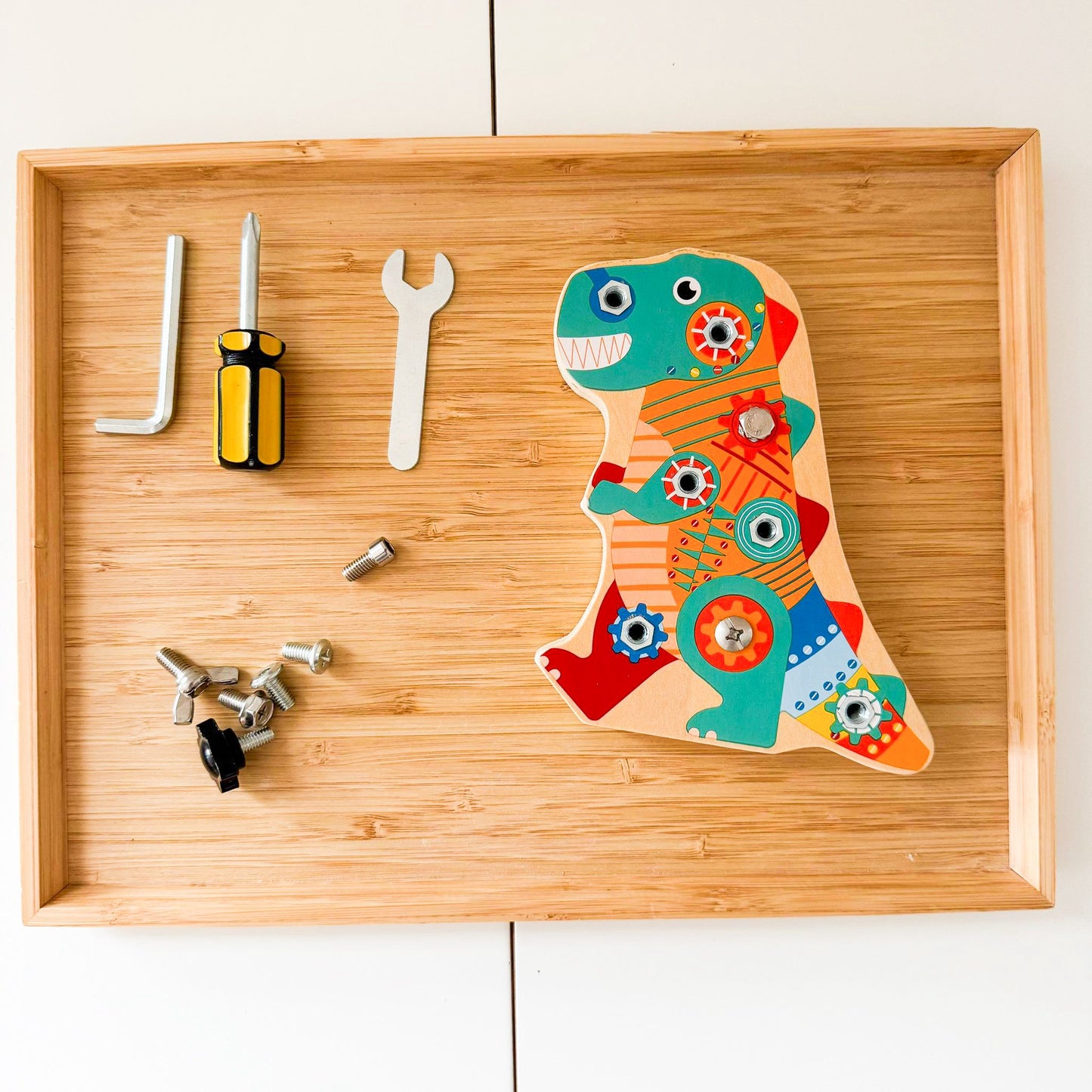 Colorful dinosaur-shaped tool set on a wooden tray