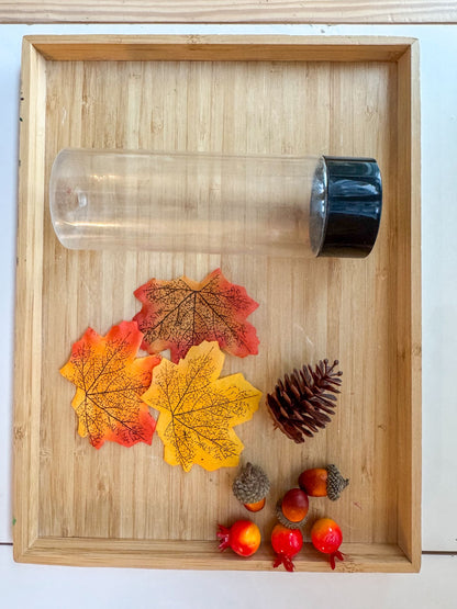 Clear glass tumbler with black lid on a wooden tray with autumn-themed decorations.